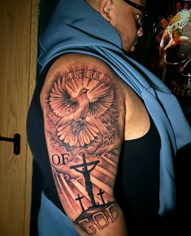 Child of God upper-arm tattoo with a dove, light rays and three crosses