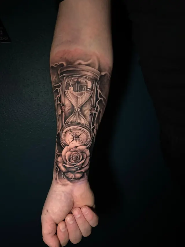 Realism forearm tattoo of an hourglass, a compass and a rose